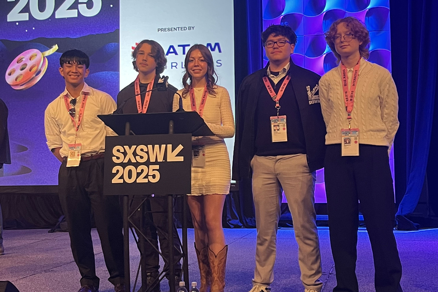 Five students stand on stage next to the SXSW 25 podium.