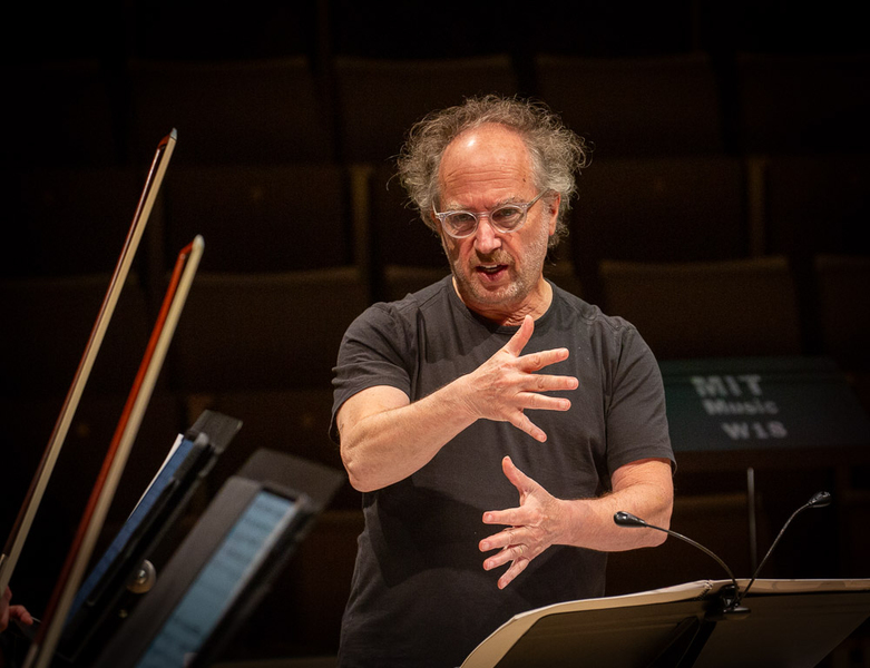 Closeup of Tod Machover standing in front of an orchestra, conducting