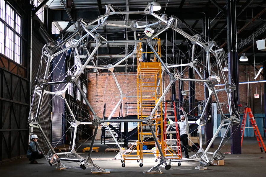 People in a warehouse building a large dome-like habitat