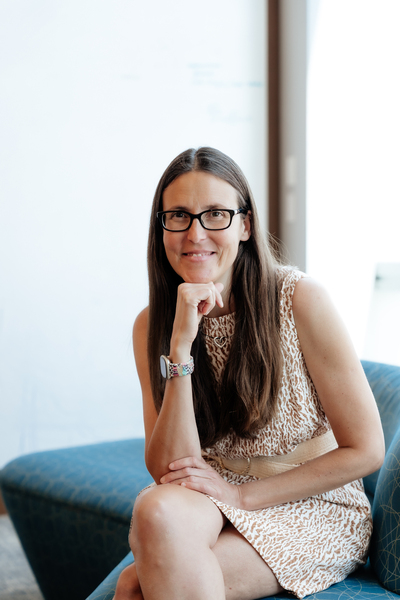 Caroline Uhler poses on a bench, resting her chin on her fist and looking thoughtfully at the camera.
