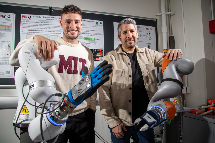 Noah Geiger and Johannes Lachner pose leaning on robotic arms in a lab