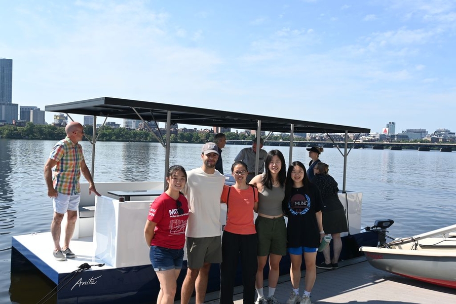 A group of five students poses in front of the boat.