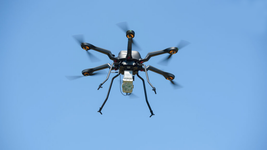 An image of a small 6-rotor drone, outfitted with a gas-mapping lidar unit, against a blue sky.
