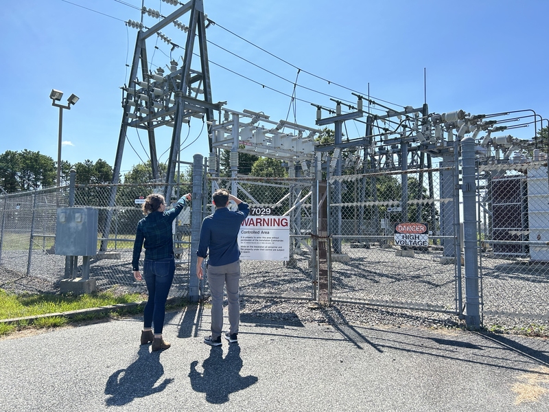 Two researchers look at a small power station outside
