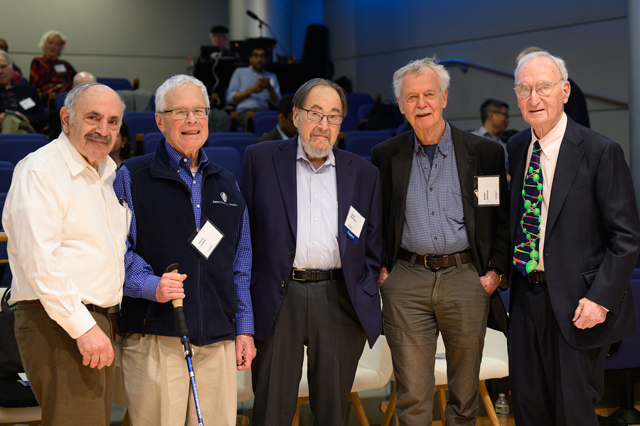 Robert Weinberg, Harvey Lodish, David Baltimore, Rudolf Jaenisch, and Gerry Fink pose together in an auditorium.