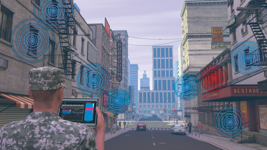 A soldier pictured from behind holds an electronic tablet with waveform signatures on it. He stands in a city center. Circles are colored blue and red around him, signifying wireless signals.