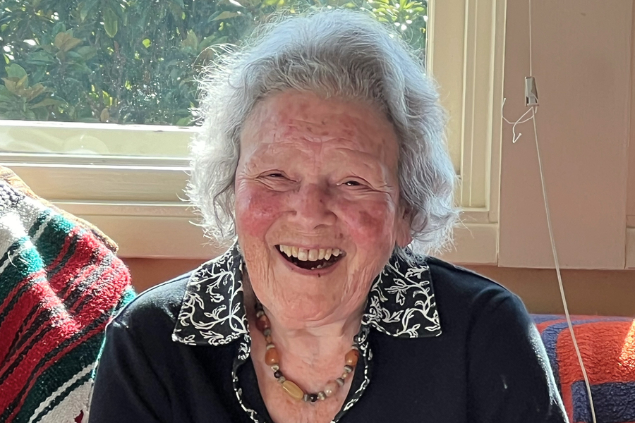 Jeanne Shapiro Bamberger laughs while seated in a sunny reading nook