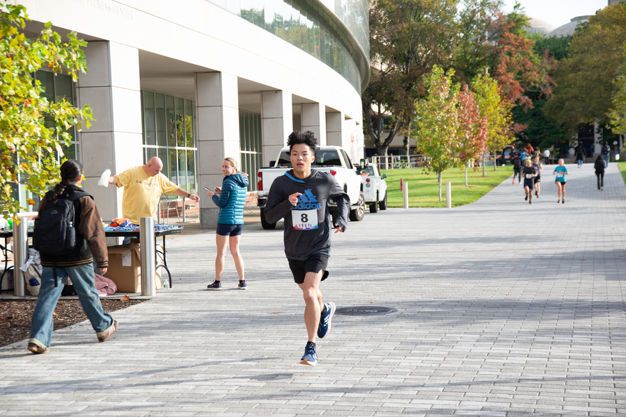 An MIT student runs in a race past a campus building