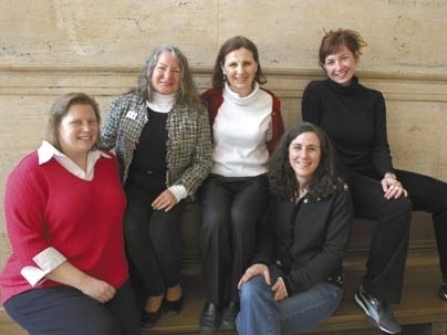 Five women sitting on and around a bench