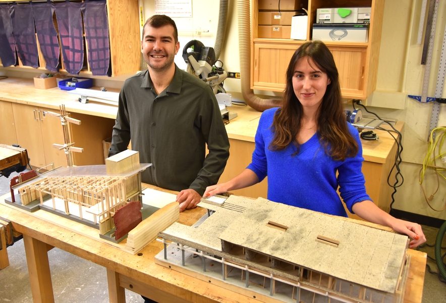 Vincent Jackow and Aleks Banaś stand behind their wood-and-stone model of a building