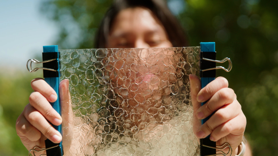 Closeup of Jacqueline Prawira holding up a translucent sheet, with cells that resemble bubble wrap