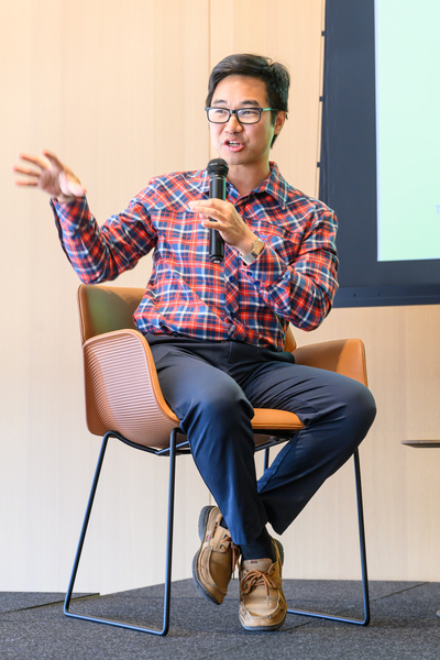 John Liu, sitting, speaks into a microphone.