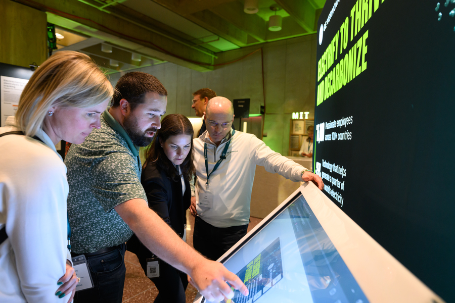 Four people look at and interact with a screen display.