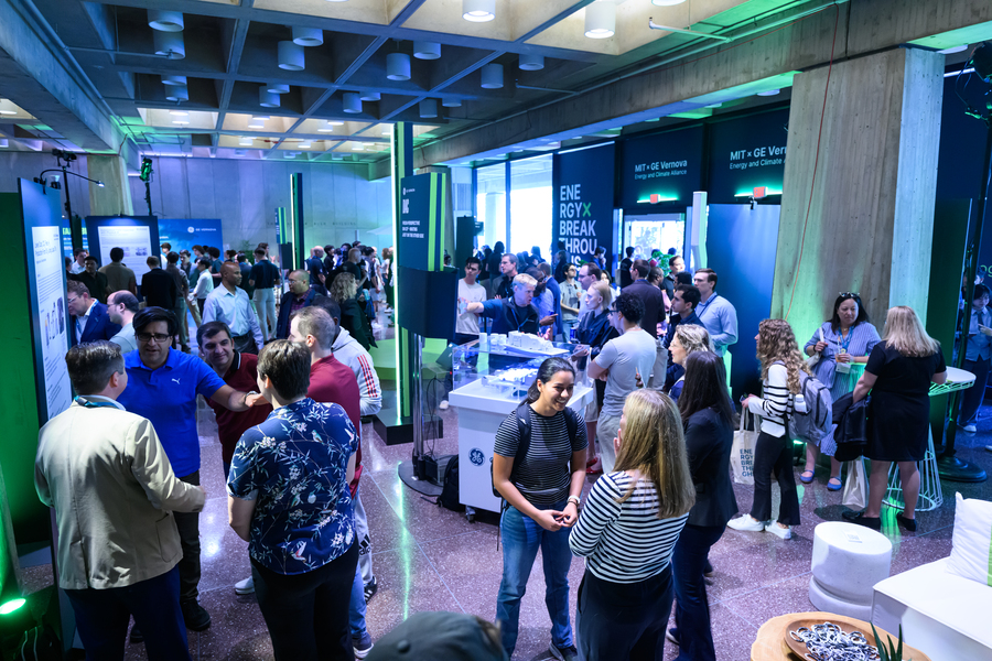 Several groups of people in conversation in a large space set up with multiple interactive displays.
