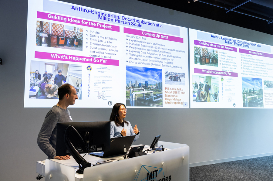 Michael Short and Manduhai Buyandelger are seated together before a set of projected slides on their anthro-engineering project.
