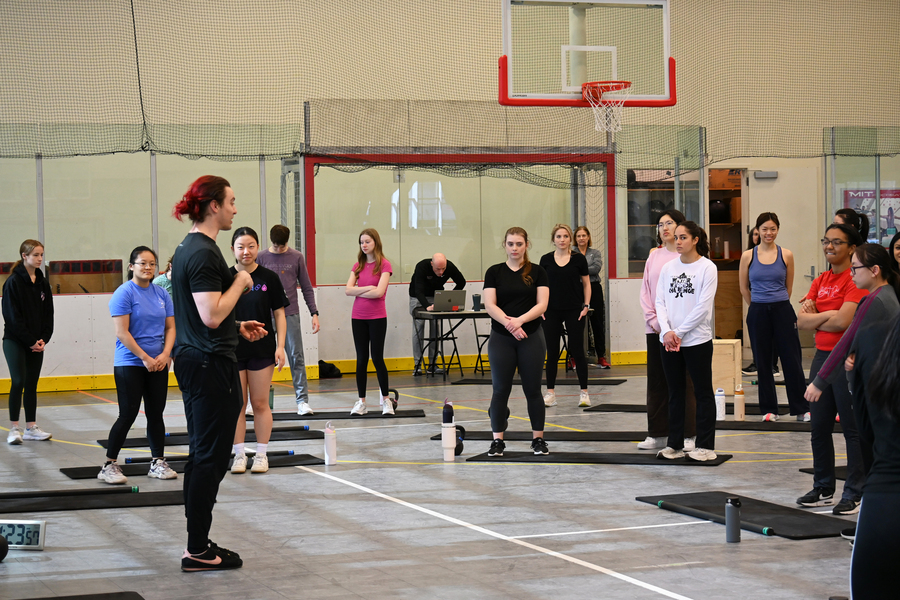 Students listening to a PE instructor in an MIT gym.
