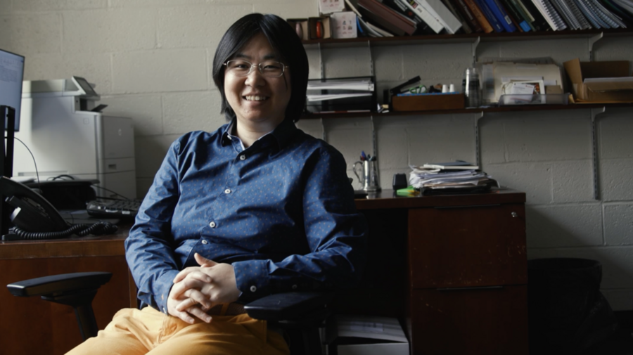 Photo of Sili Deng seated in a small office with shelves behind her