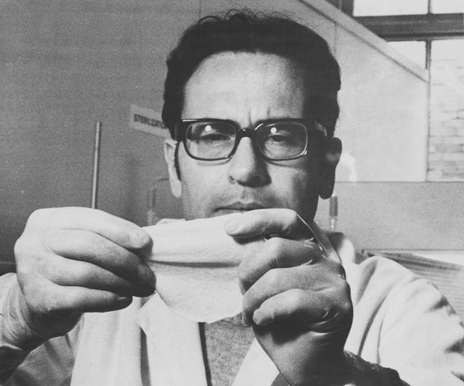 Greyscale photo of a young Ioannis Yannas, holding a 3-inch-wide sample of artificial skin