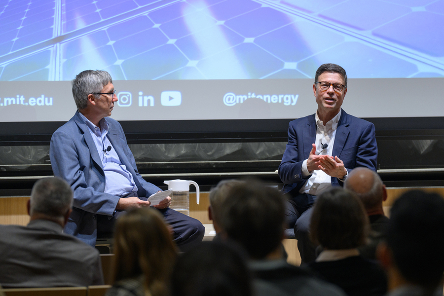 Kurt Kelty speaks on a stage with William Green looking on. Both are seated.