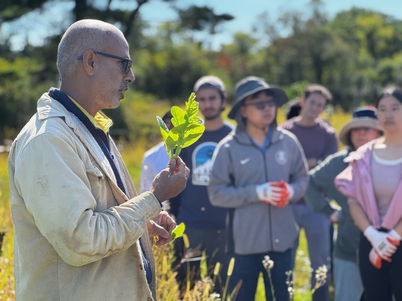 Mohammed Hannan holds a piece of spinach while talking to a group of people at a farm.
