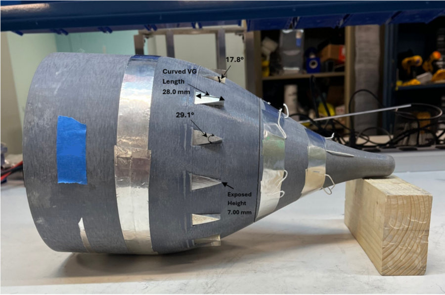 A physical model of a ship's hull: gray, shaped like a cone, laying on its side, with various dimensions labeled.