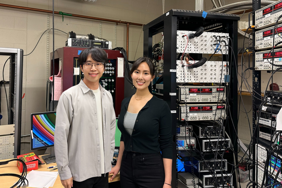 Shuwen Sun and Jeong Min Park stand in front of large scientific equipment in a lab
