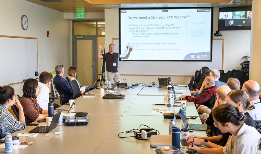 Christopher Knittel stands before a large conference table giving a presentation to about a dozen others