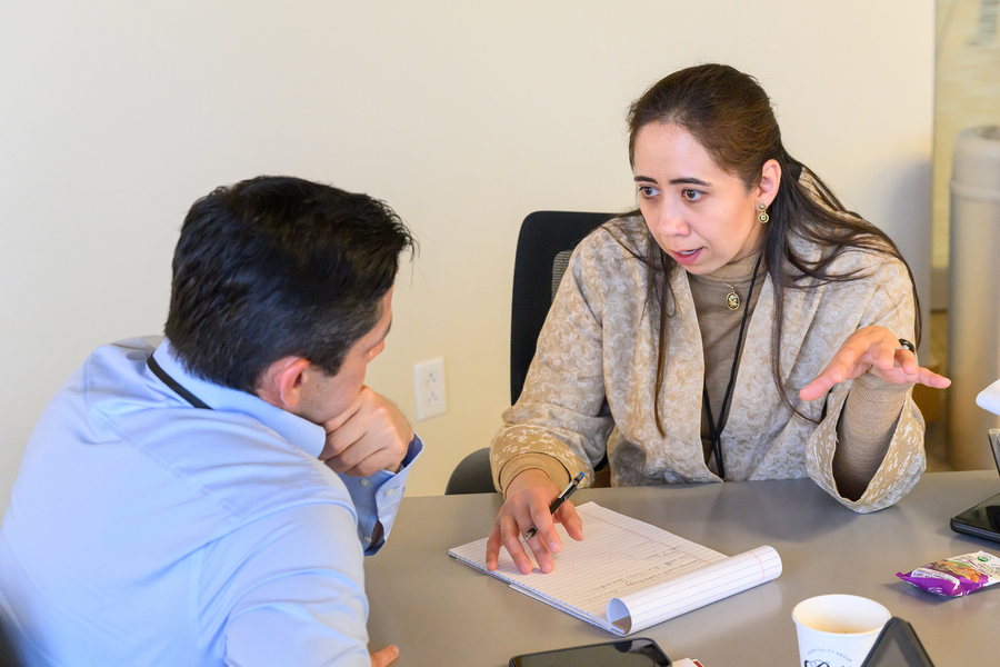 Janelle Knox-Hayes sits at a table in discussion with a man whose back is to the camera