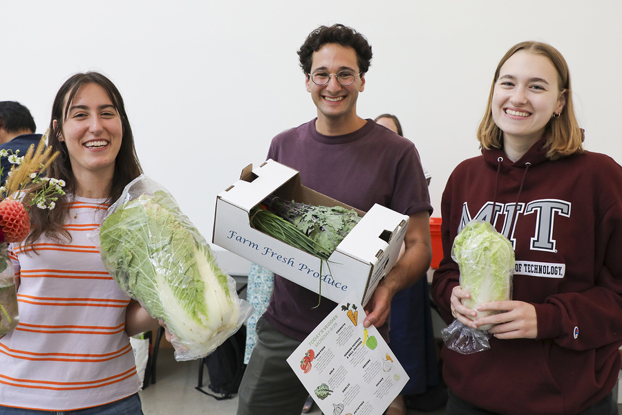 Aleks Banas, Zachary Rapaport, and Kahlen Wheaton smile for a photo indoors, holding produce.