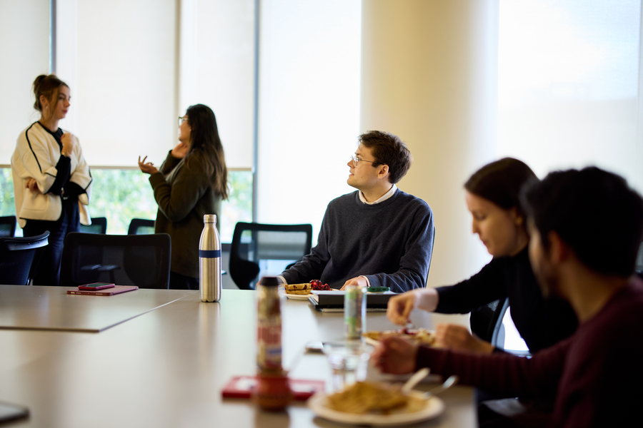 Alex Busch sits at a table indoors with several other people