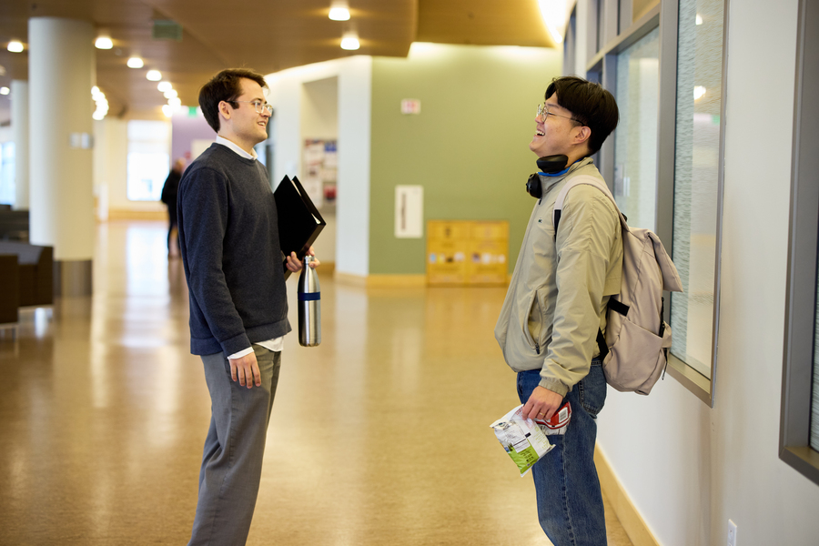 Alex Busch and another student converse in bright hallway