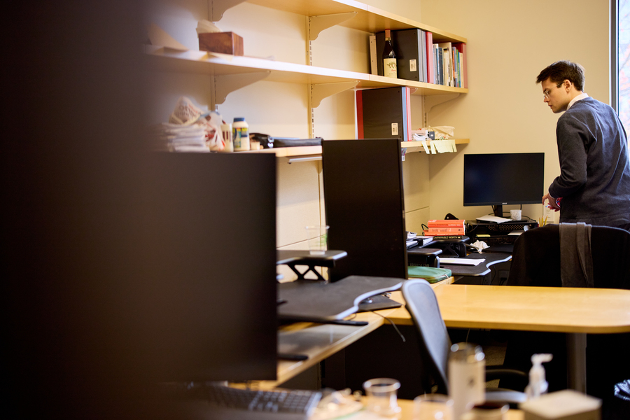Intentional blurred left side of the photo frames desk area. Alex Busch is on the right side of the frame approaching a desk