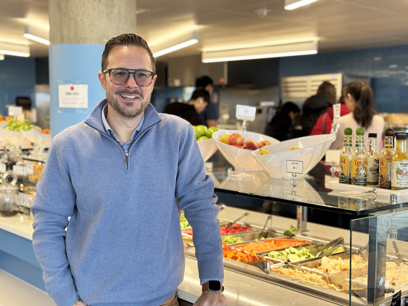 Andrew Mankus posing next to a salad bar in an MIT dining hall