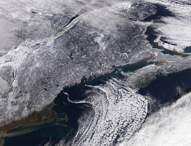 Satellite black-and-white image showing the northeastern United States. Cape Cod and the southeastern coast as far as Long Island are visible through a gap in the clouds