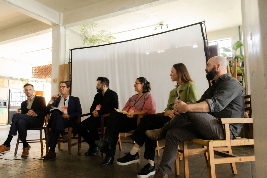 Six people sitting down, one of them speaking on a mic
