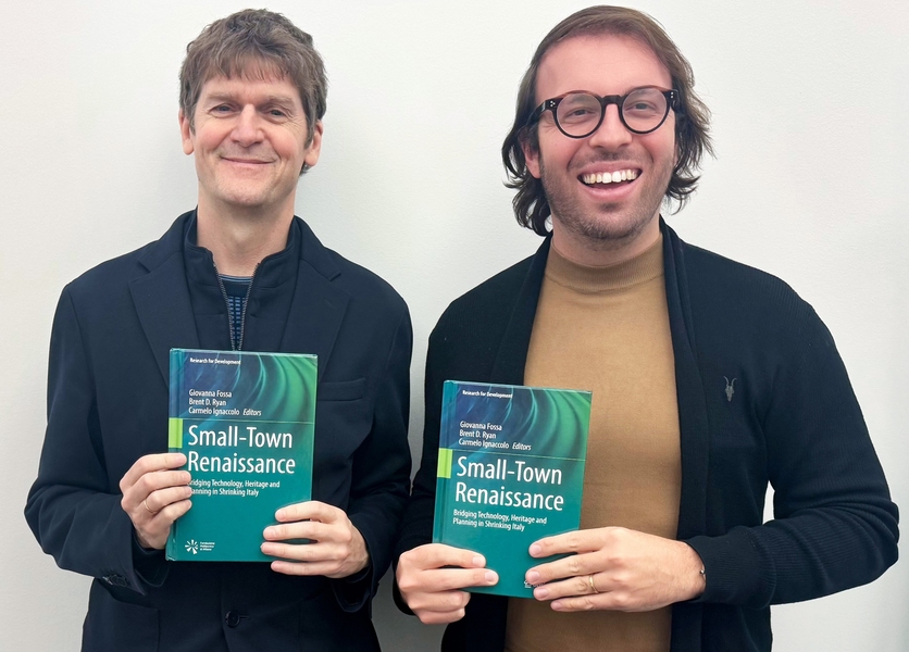Brent Ryan and Carmelo Ignacolo pose together, each holding up the book “Small Town Renaissance: Bridging Technology, Heritage and Planning in Shrinking Italy.”