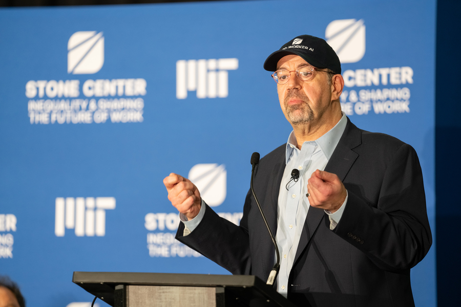 Daron Acemoglu, wearing a "pro-worker AI" baseball cap, speaks at a lectern