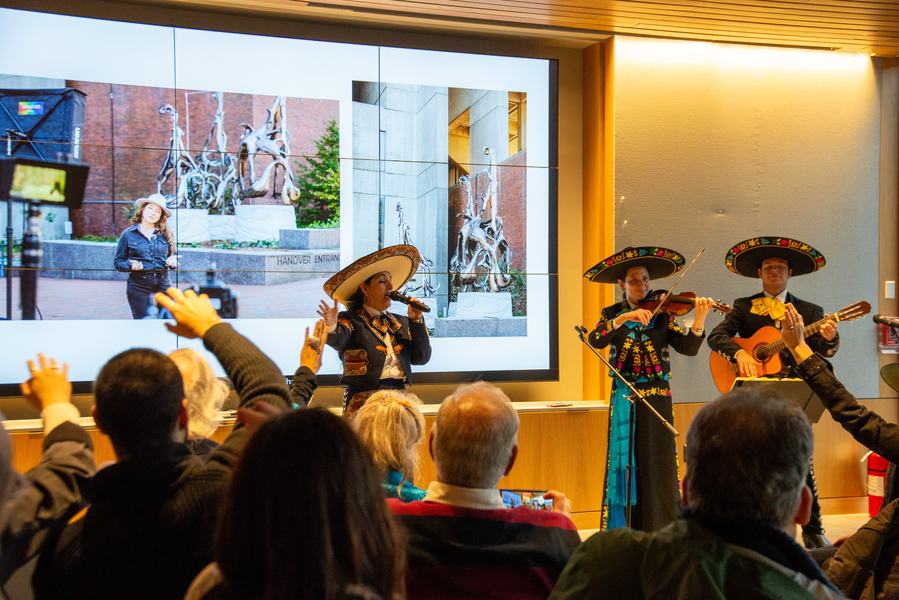 Three mariachi musicians perform on an indoor stage at the “Amulet” ribbon-cutting event