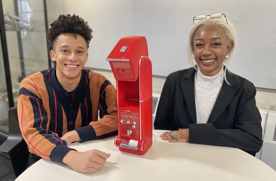 Jacob Payne and Ayah Mahmoud sit at a table, atop of which sits a bright red Kitchen Cosmo device sits