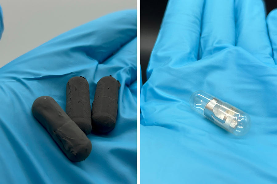 Gloved hand holds the pill-shaped capsules. Left is matte black and right is clear with shiny zinc.