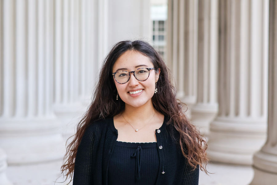 Katie Spivakovsky stands before outdoor columns at MIT