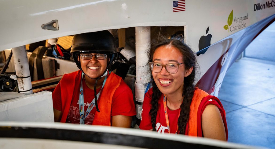 Close-up of Adrienne Lai and Deepta Gupta posing next to an electric vehicle
