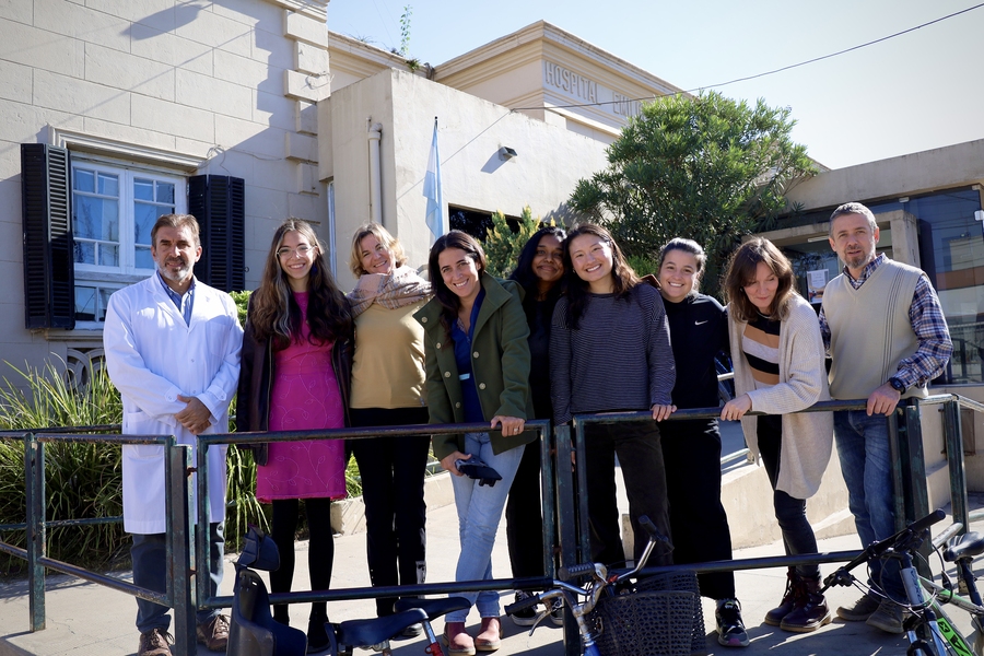 Nine people, including Srihitha Dasari, stand posing together outside of a hospital.