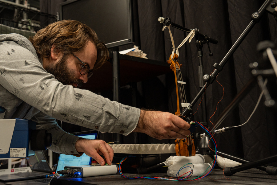 Mark Rau places an impact hammer near an antique violin.