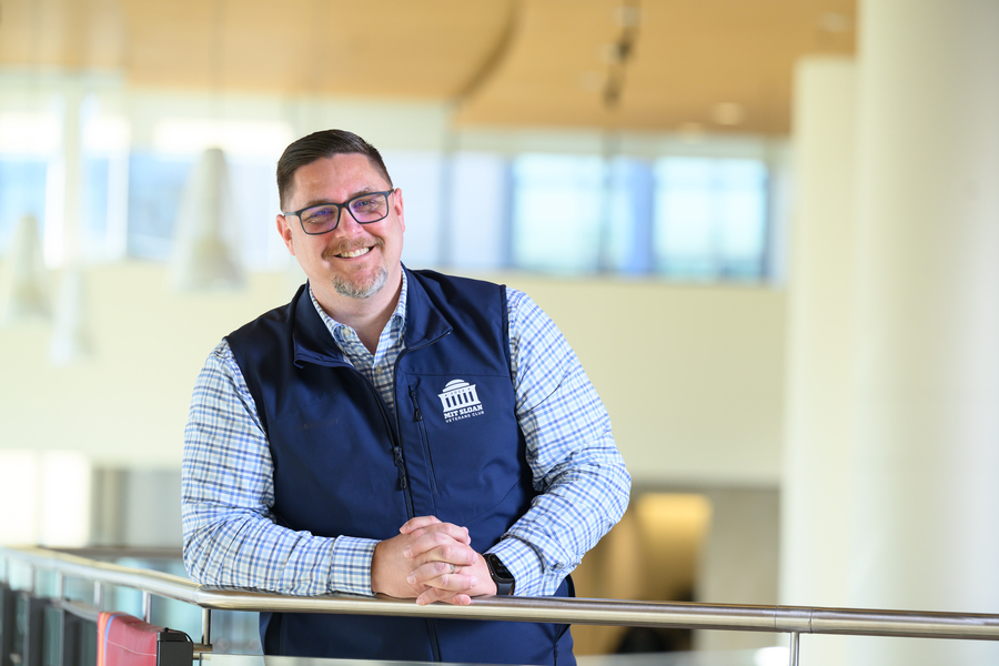 Greg Knutson leans on a balcony railing in a sunlit atrium
