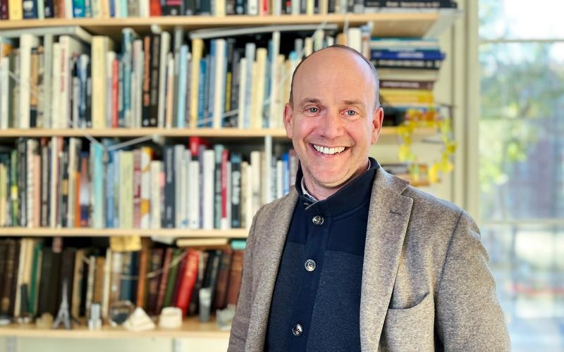 John Ochsendorf standing in front of a bookcase