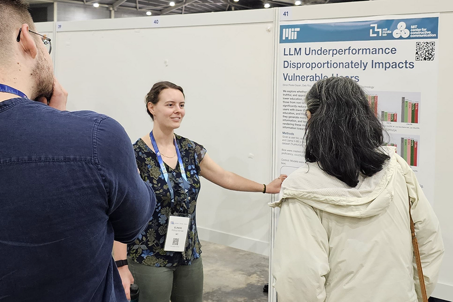 Elinor Poole-Dayan presents a paper poster to two people