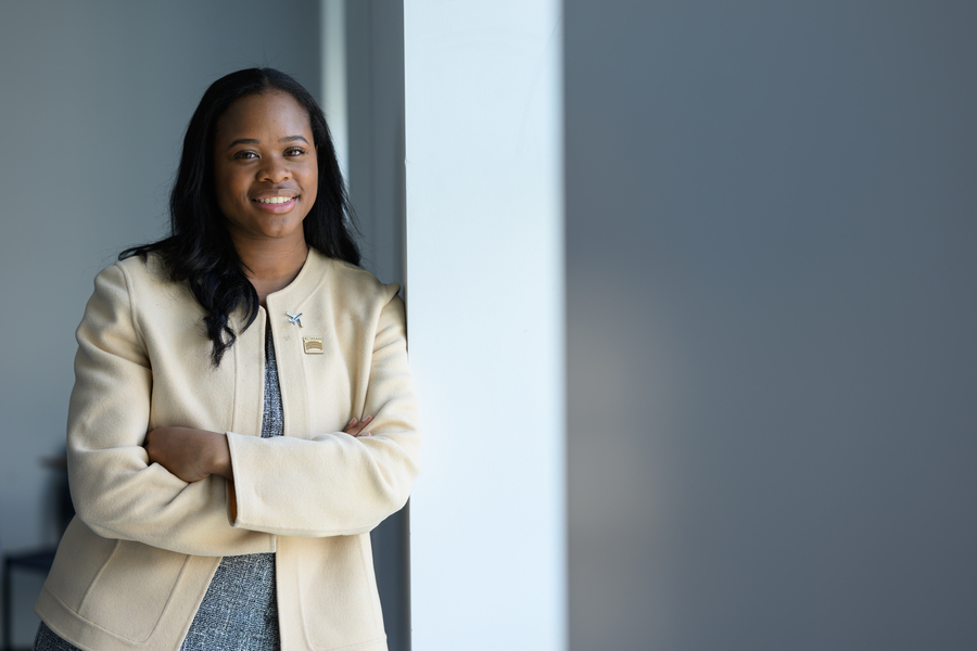Carissma McGee poses standing with arms folded, leaning against a wall