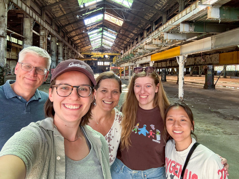 Sara Jex takes a selfie with four family members inside a large, abandoned industrial warehouse