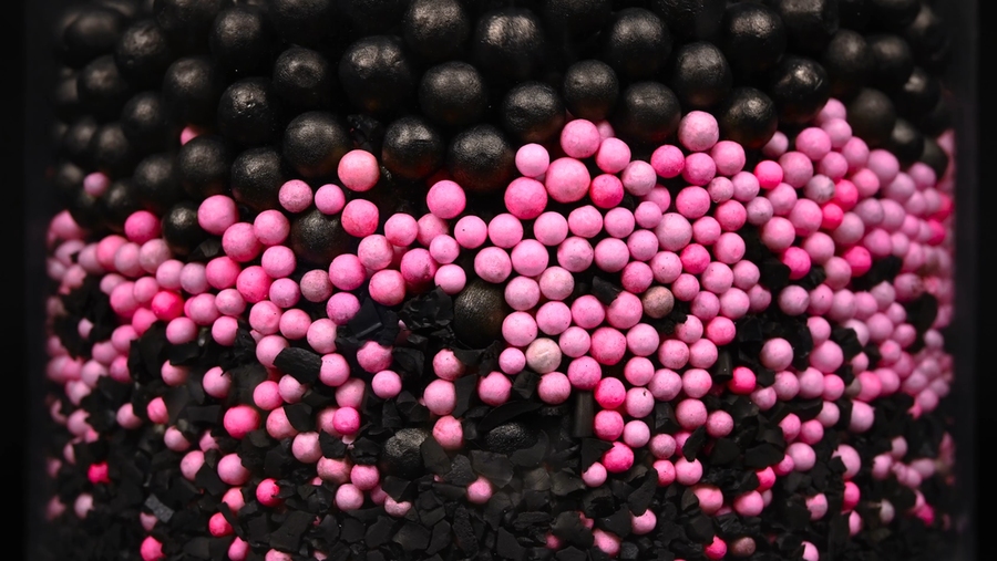 Closeup photo of a mix of small pink plastic balls and larger black plastic balls